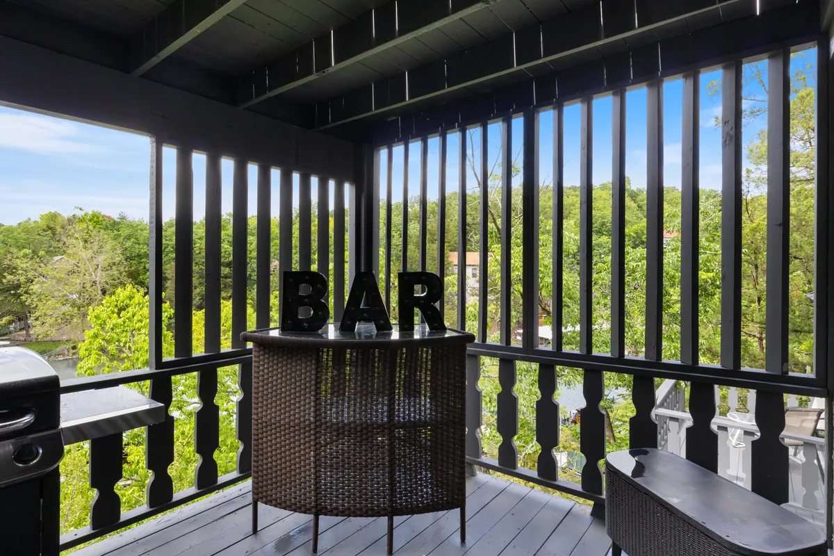 An exterior space with a lively bar, ample outdoor seating, and lush greenery sets a cheerful, social mood. The area invites guests to gather after a day on the lake for sunset drinks, laughter, and storytelling.