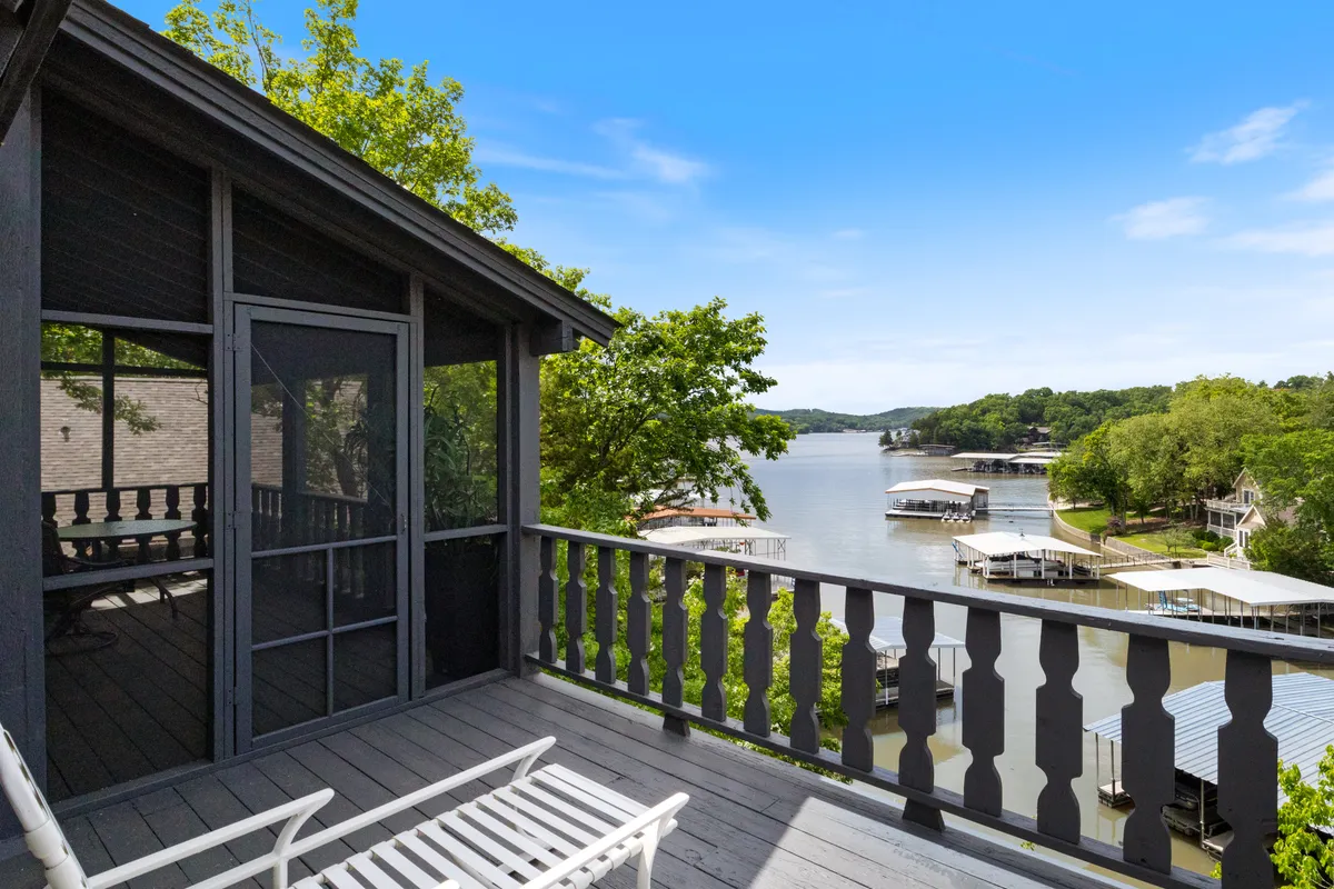 The image showcases a tranquil waterfront view from the house, with lush greenery framing the scene, a peaceful dock extending into the lake, and a spacious screened porch perfect for relaxing or gathering. The setting exudes serenity and invites guests to enjoy outdoor activities or simply unwind while taking in the natural beauty.