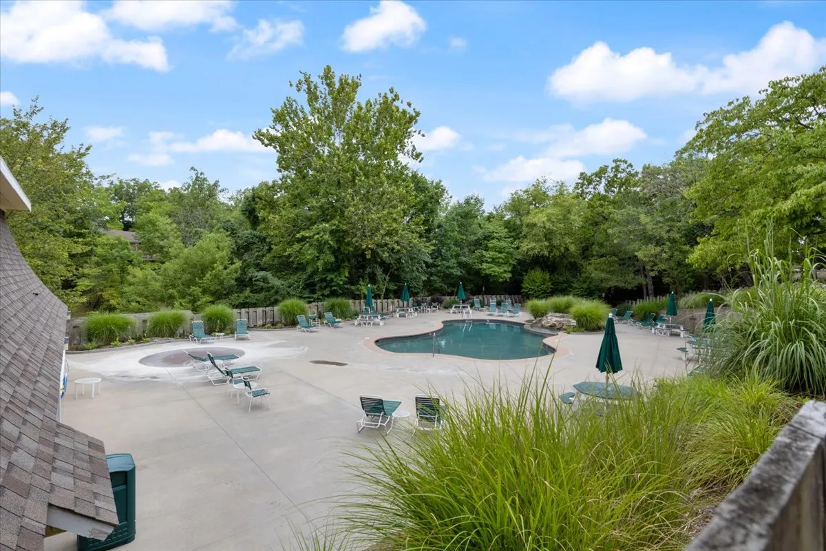 This inviting exterior shot features a sparkling swimming pool surrounded by lounge chairs and lush greenery, with the tranquil waters reflecting the sky. The scene hints at both relaxation and recreation, with room for sunbathing, social gatherings, and cooling off after a day on the lake.
