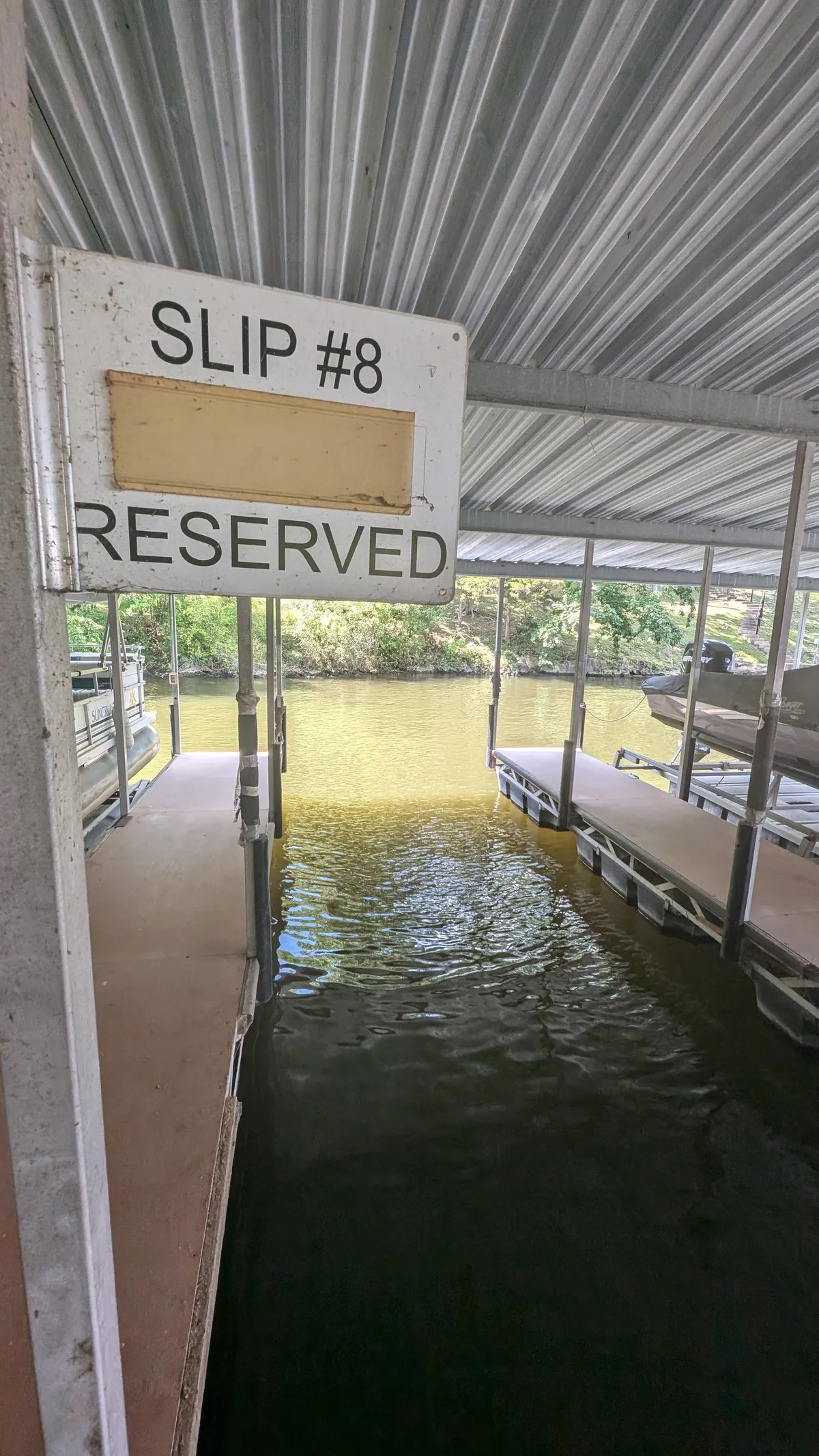 The photo focuses on a dock structure labeled 'Slip #8,' with placid water and a serene ambiance. The setting is quiet, perfect for boating and fishing, underscoring the exclusive, effortless lake access described in the section.