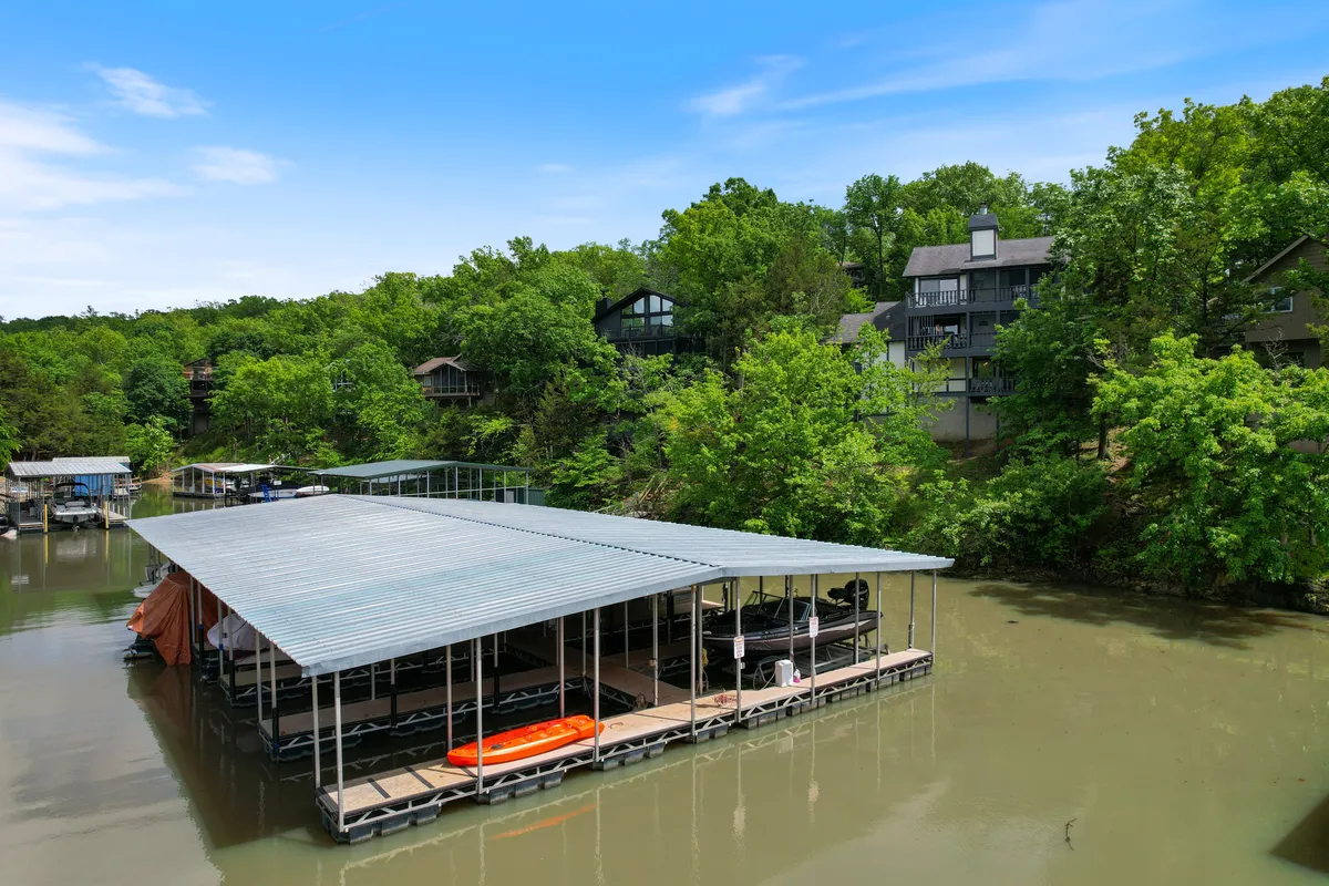 This image displays a tranquil waterfront scene featuring boat docks, a kayak, verdant greenery, and residential buildings. The water is calm, inviting for boating or kayaking, and the setting is peaceful and inviting for lakeside relaxation.