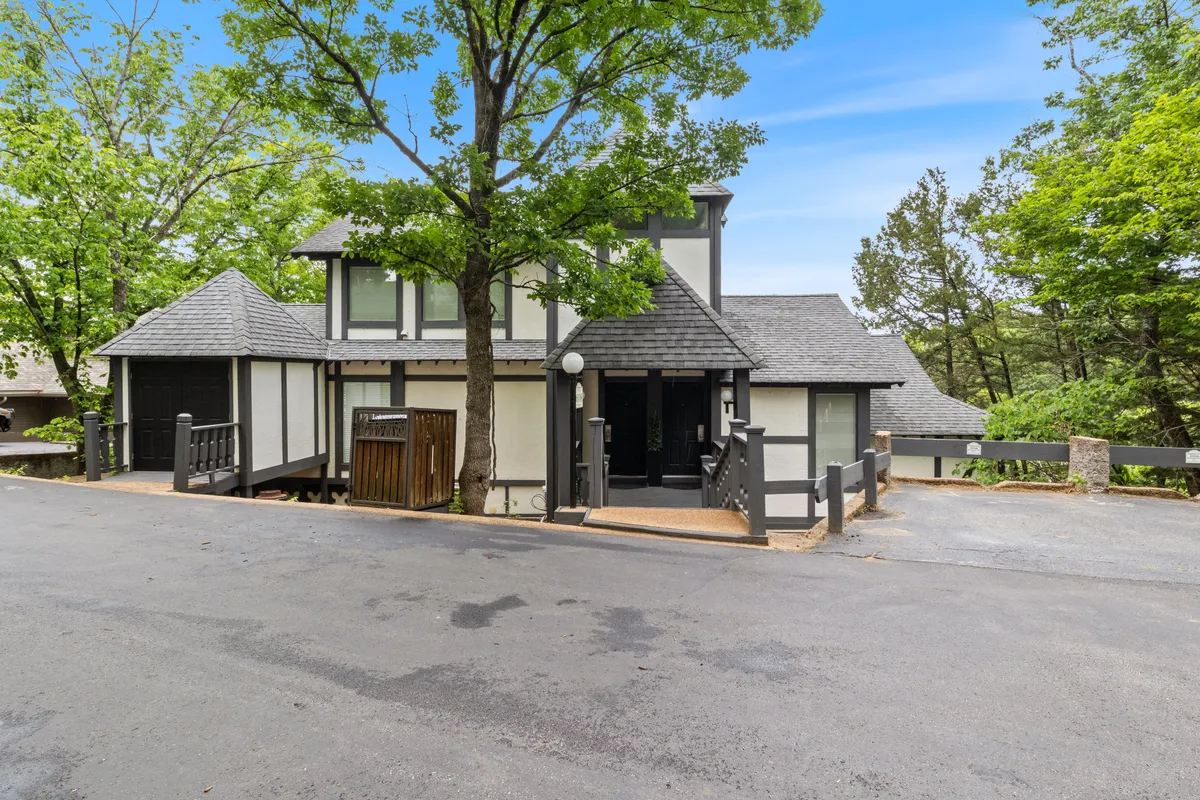 The house's welcoming facade framed by a large tree and driveway, suggesting space for family arrivals, outdoor relaxation, and access to nature walks. The porch hints at a spot for morning coffee or evening relaxation.
